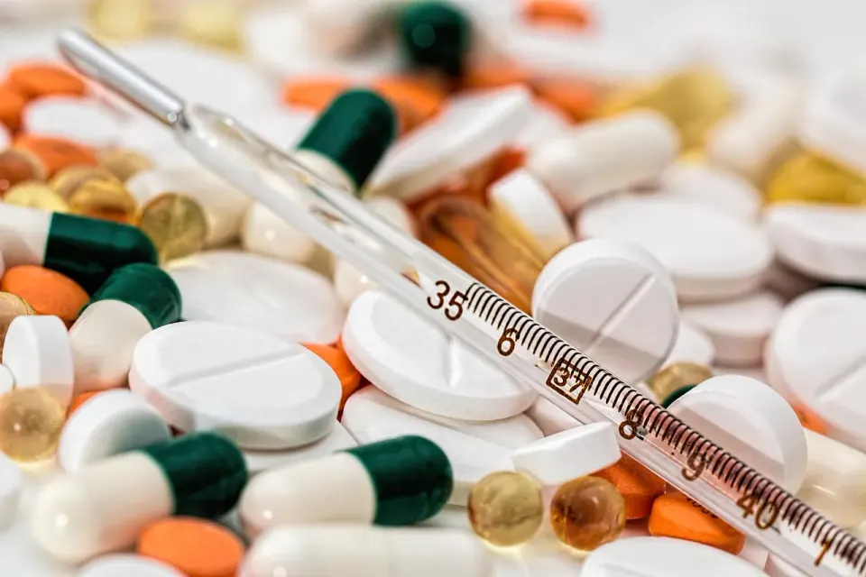 Thermometer and assorted medication tablets on a table