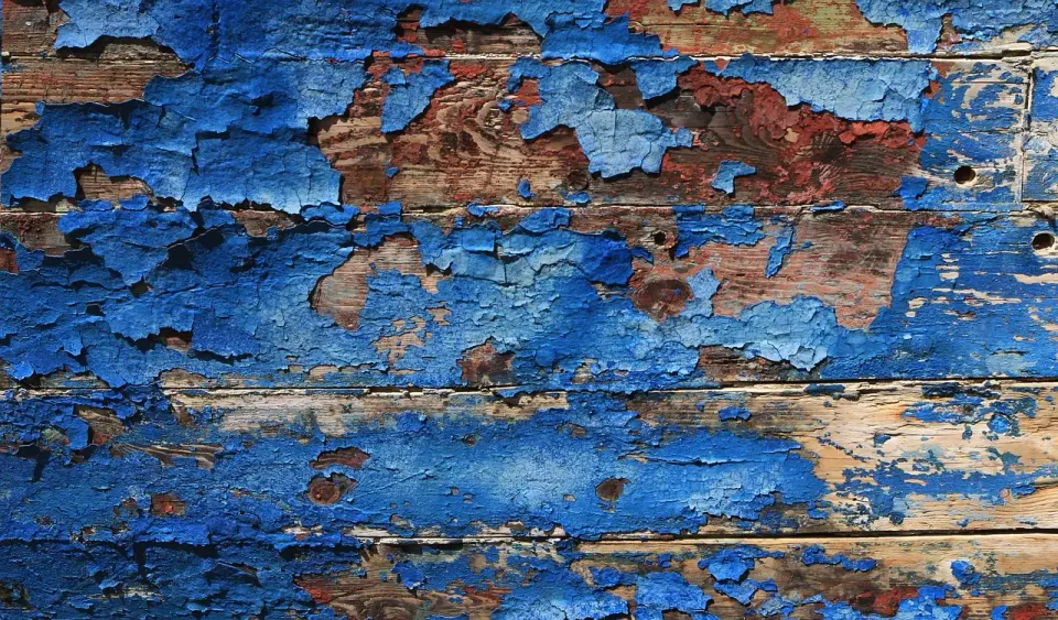 Peeling blue paint on an old painted wall