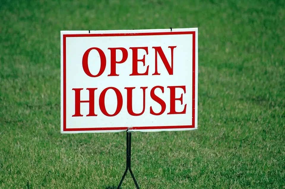 Open house for sale sign on a front lawn
