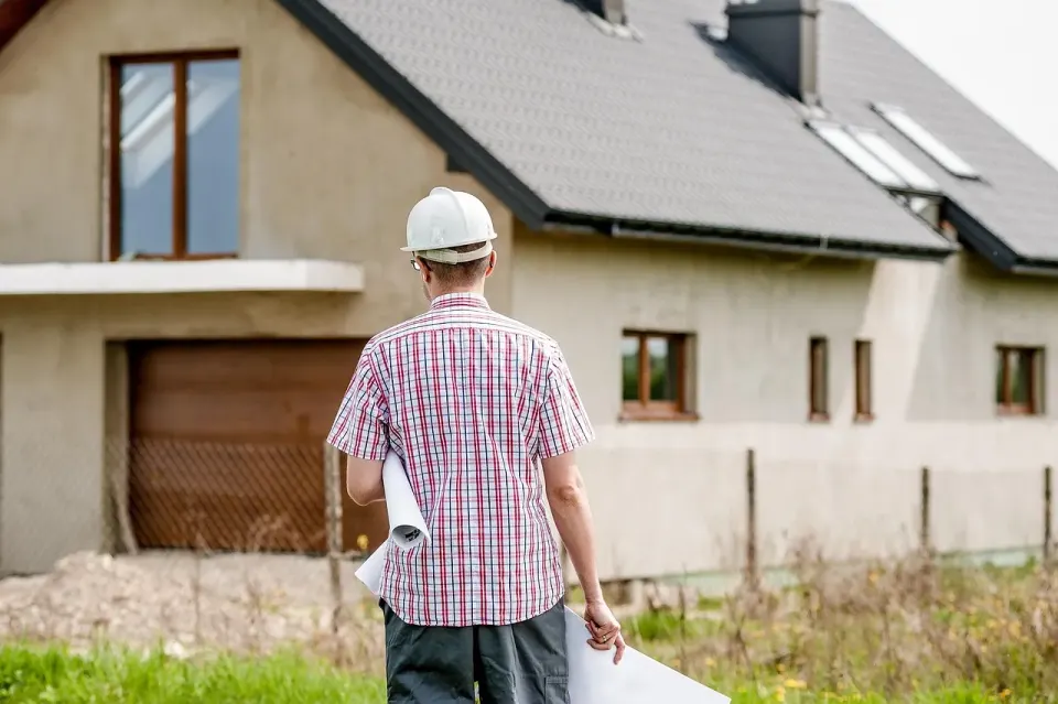 Man holding building plans while looking at a newly built house