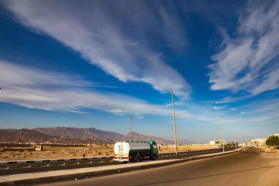 Truck driving along a highway under a wide blue sky