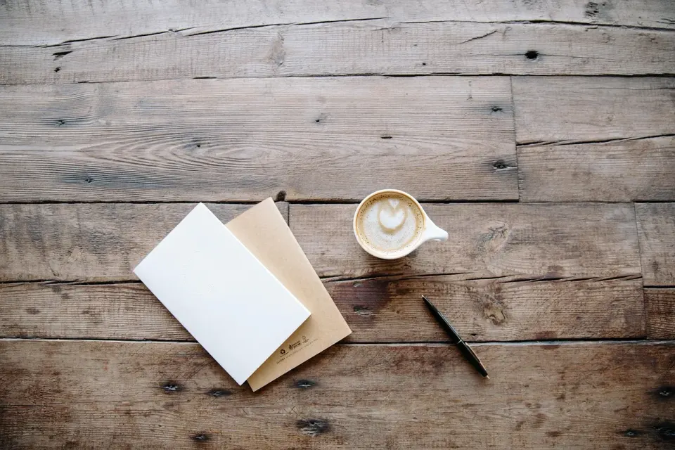 A pen and blank paper on a wooden desk, ready for a written notice