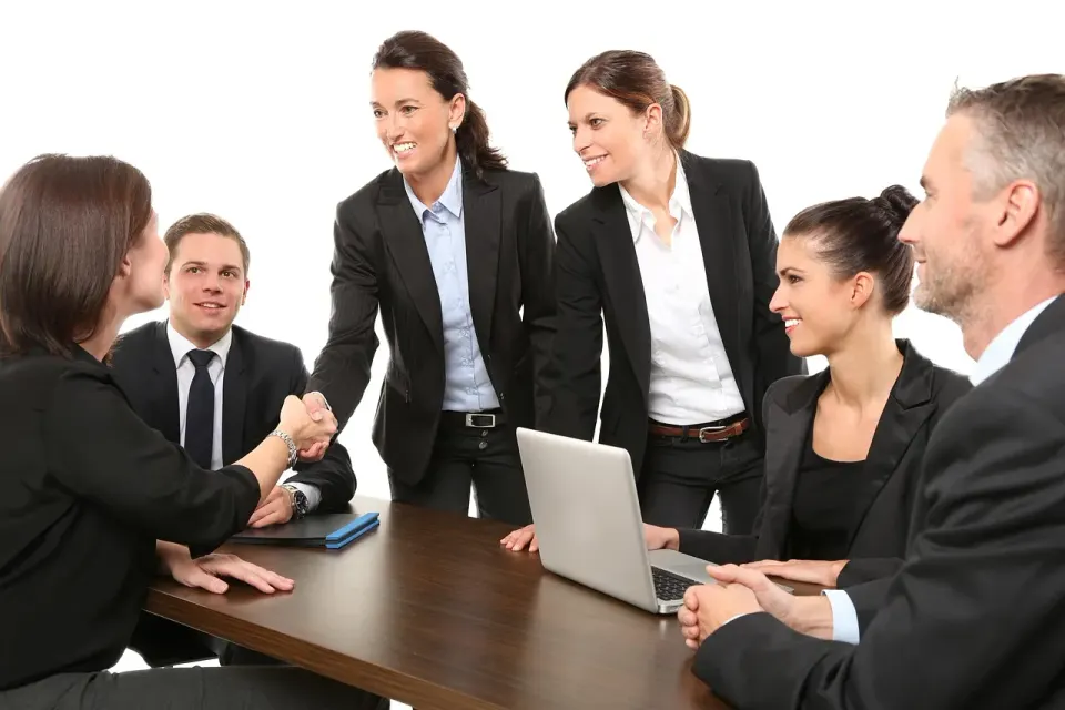 Two people shaking hands across a table after a meeting