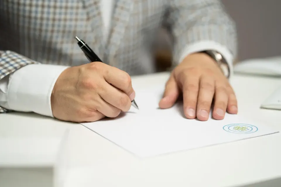 A person signing a printed document at a desk