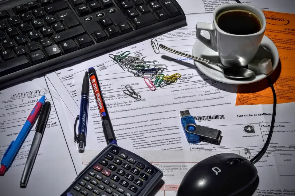 Person working through receipts and paperwork at a desk with coffee