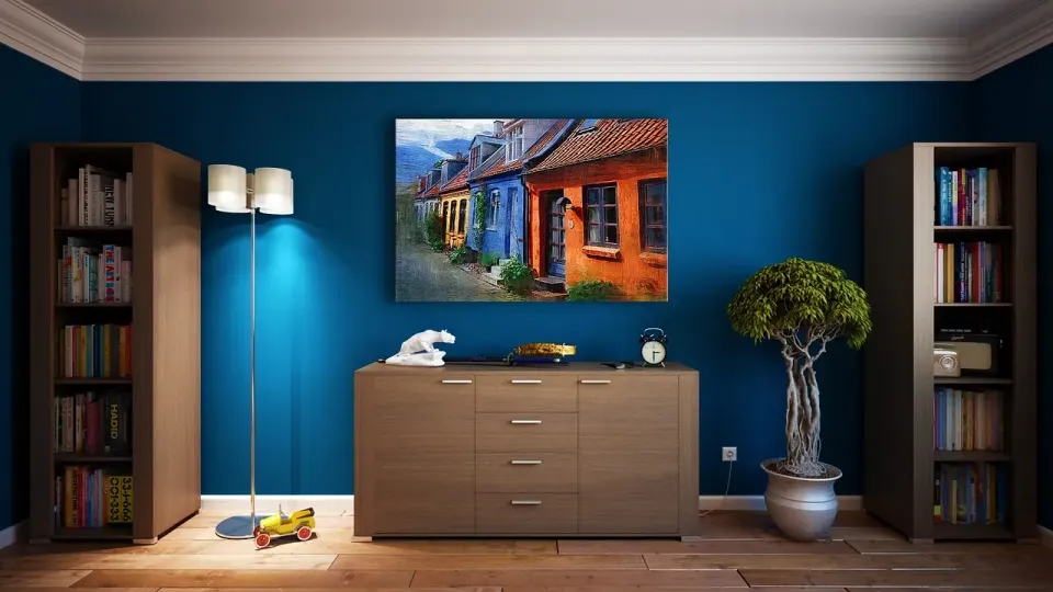 Freshly painted blue living room with bookshelves and a wooden dresser